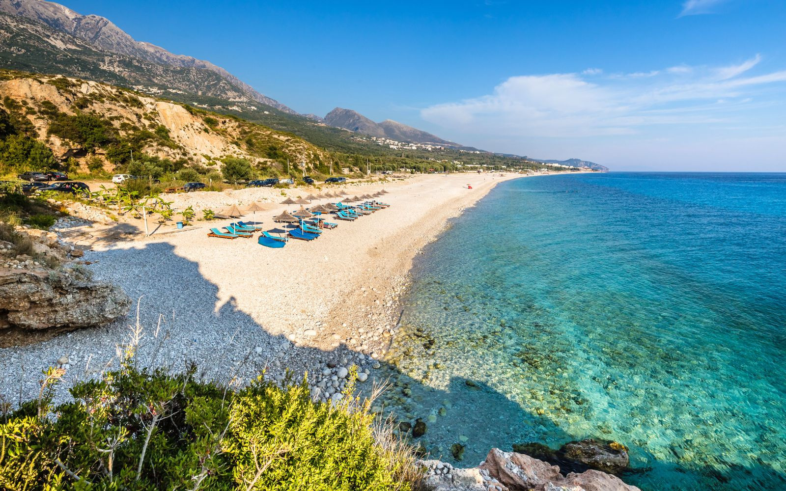 Golden sand and clear blue waters of Dhermi Beach, surrounded by mountains