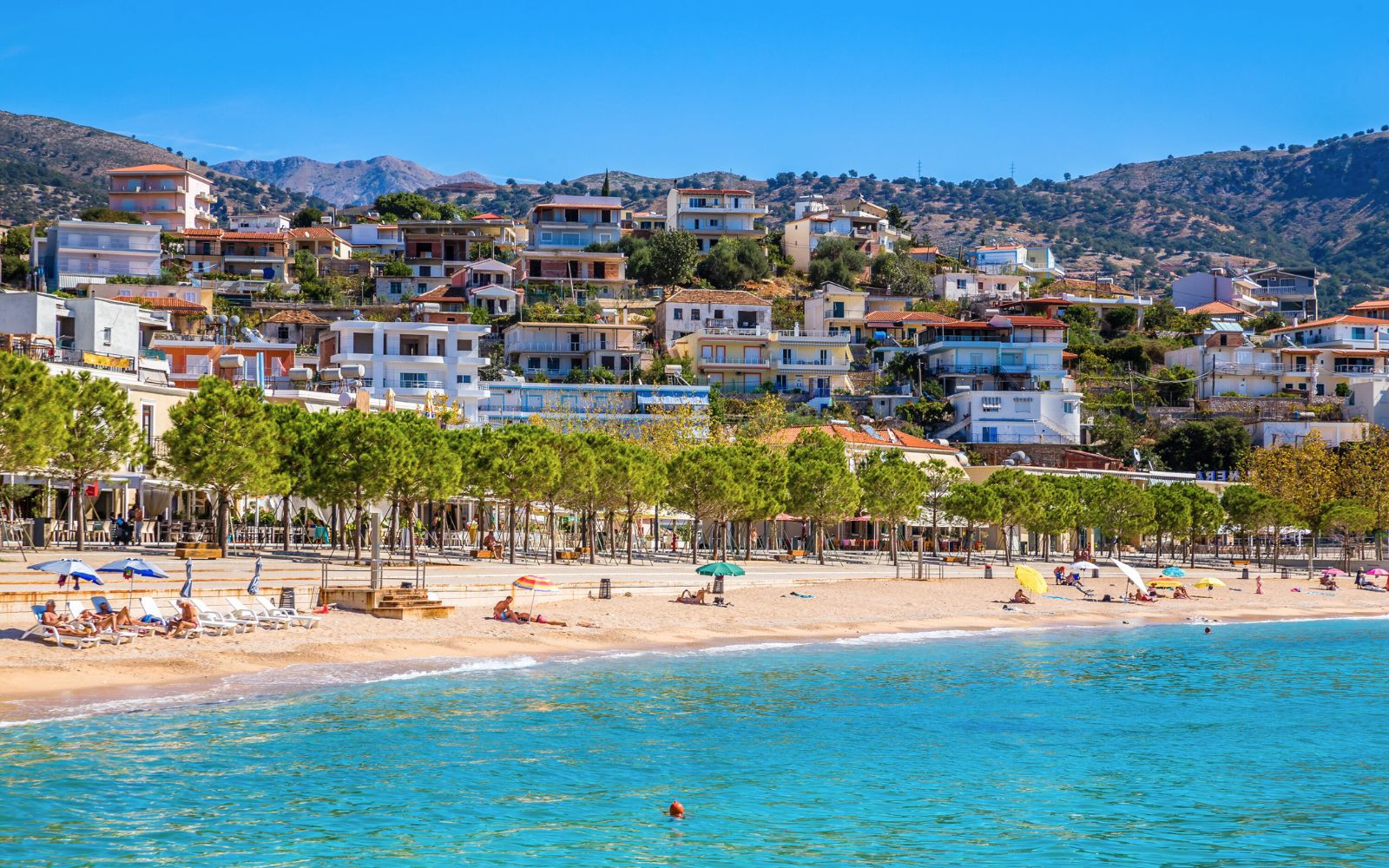 Himare beach and village behind bright blue waters