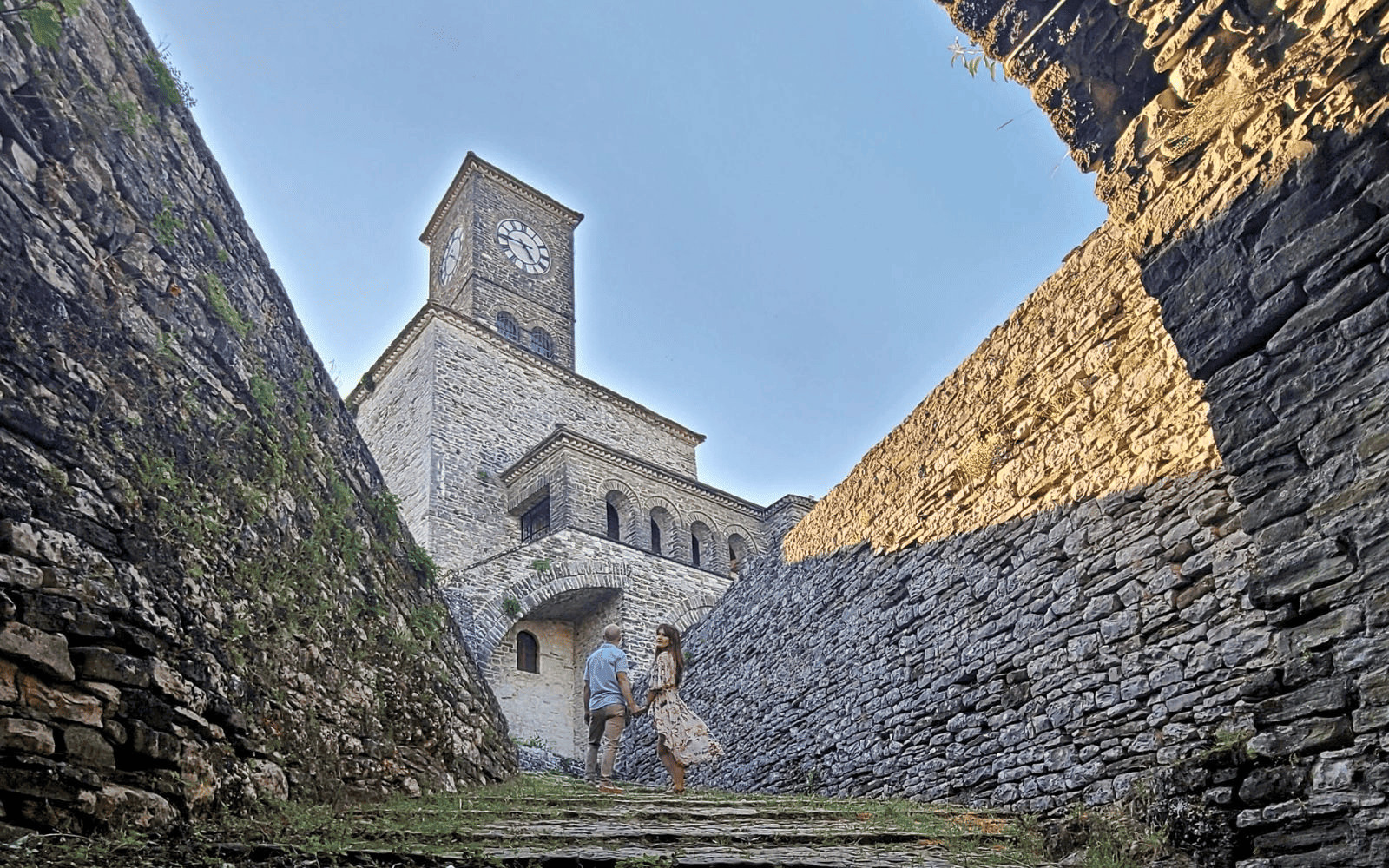 Couple standing in front of the clock tower of Gjirokaster Castle, one of the best things to do in Gjirokaster, Albania-photo by Abby Davis