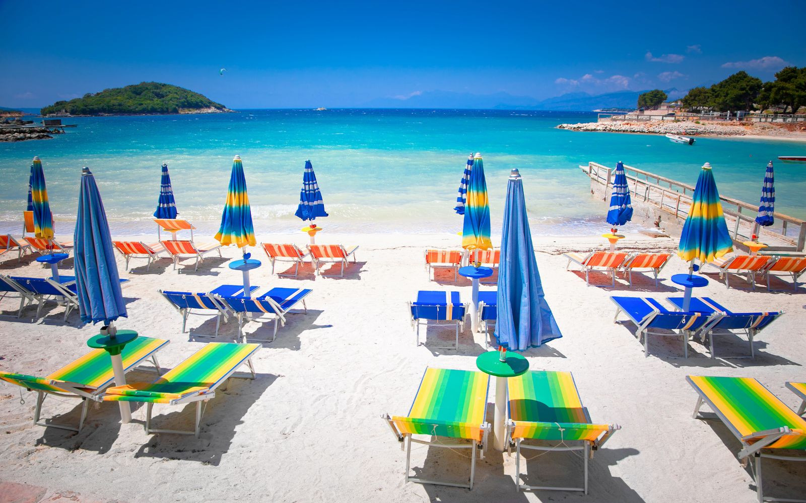 Beach chairs and umbrellas on the white sand of Ksamil Beach, Albania with crystal clear waters in the background