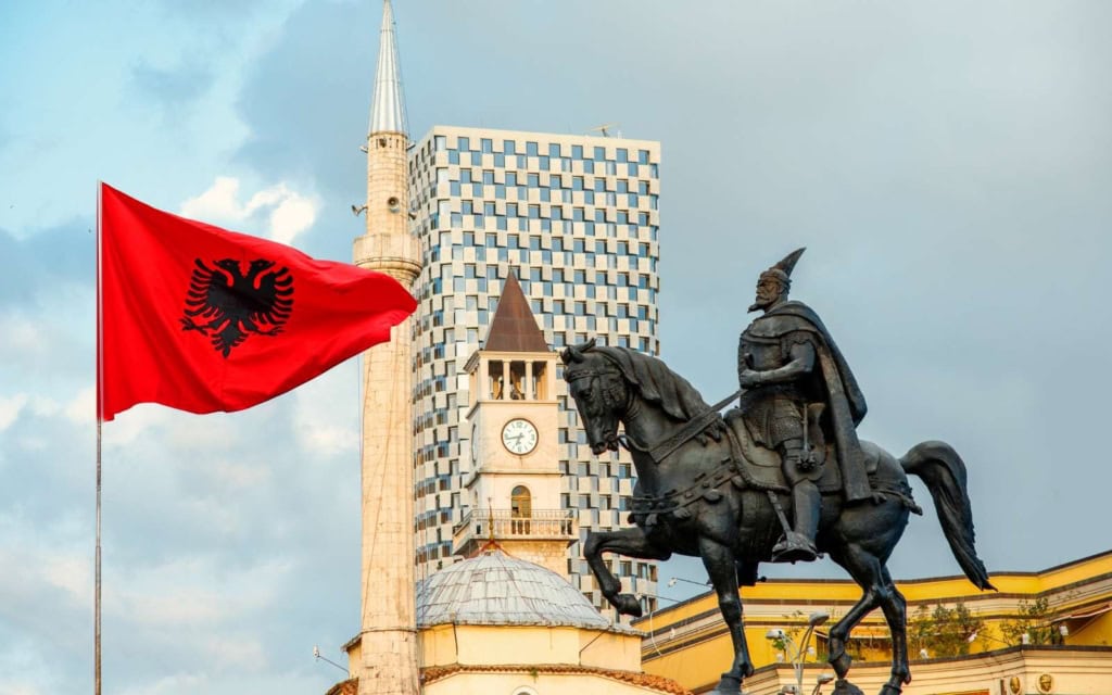 Man on horseback statue, clock tower, and Albanian flag in Skanderbeg Square one of the top places to stay in Tirana