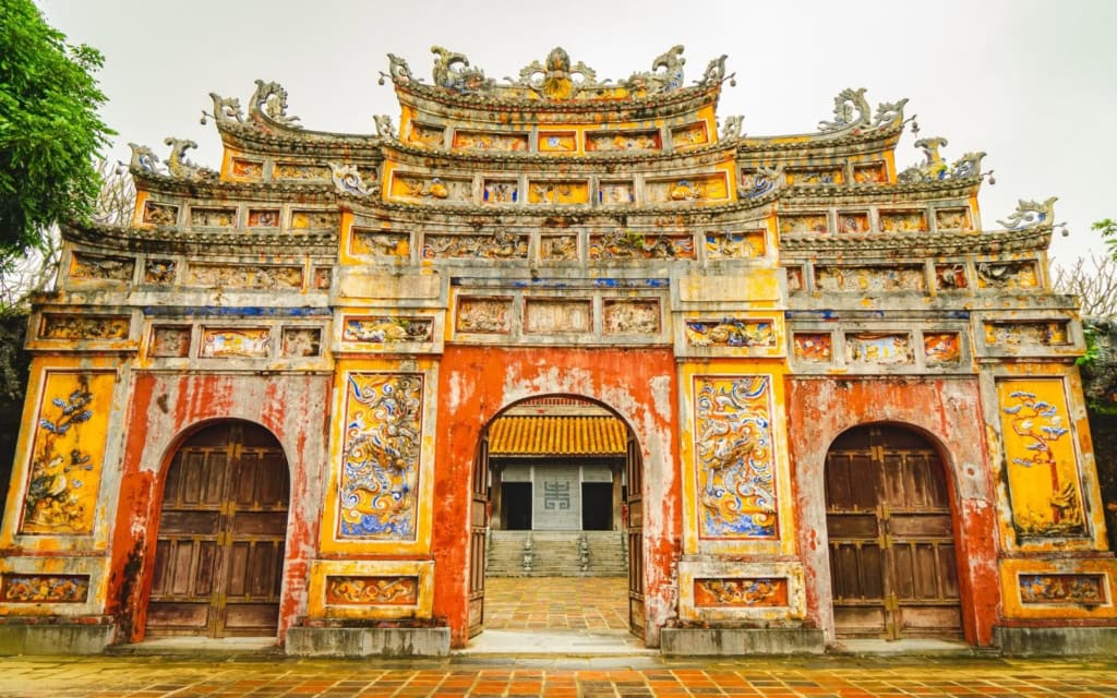 Ancient gate in the Hue with red and yellow paint and reliefs