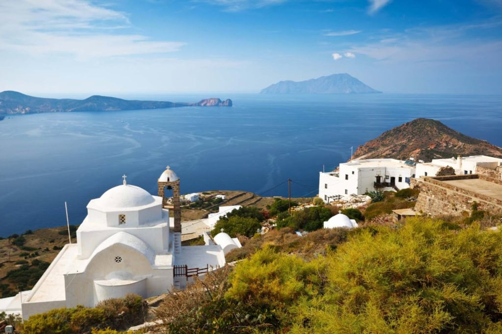Stunning view of Santorini’s white churches and blue waters, perfect for travel photography and vacation planning.