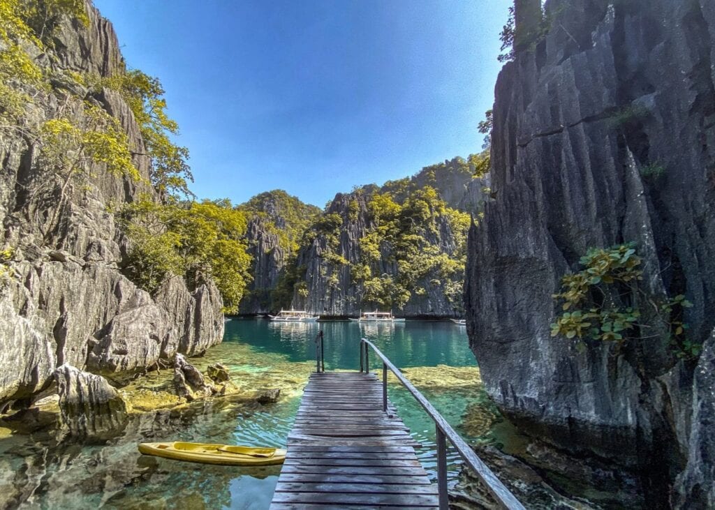 Wooden walkway and kayak in Coron lagoon surrounded by rocky crags