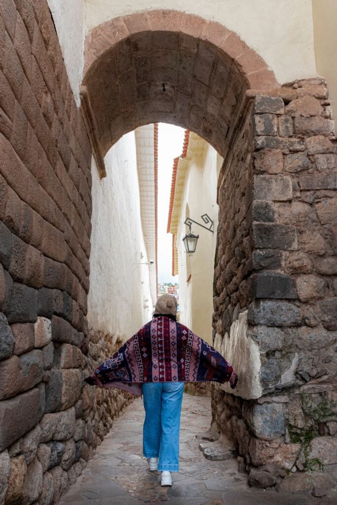 woman standing in the middle of a small pathway at Seven Snakes Street Cusco