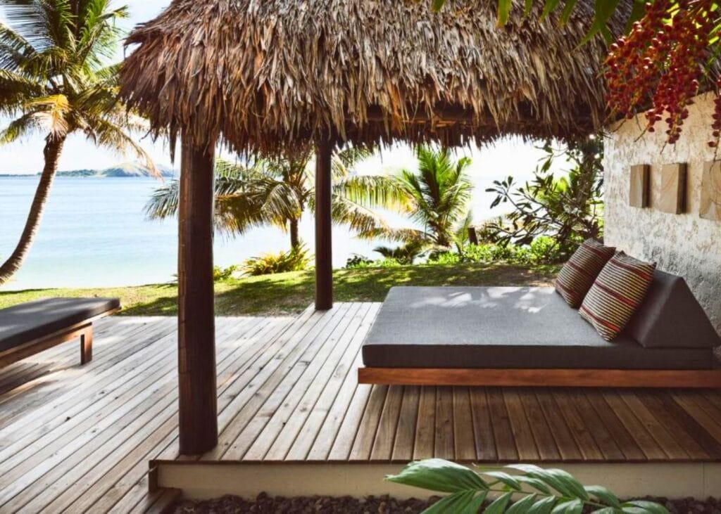 Tiki hut and outdoor bed with sun terrace and palm trees overlooking the Pacific Ocean of Fiji at Tokoriki Island Resort