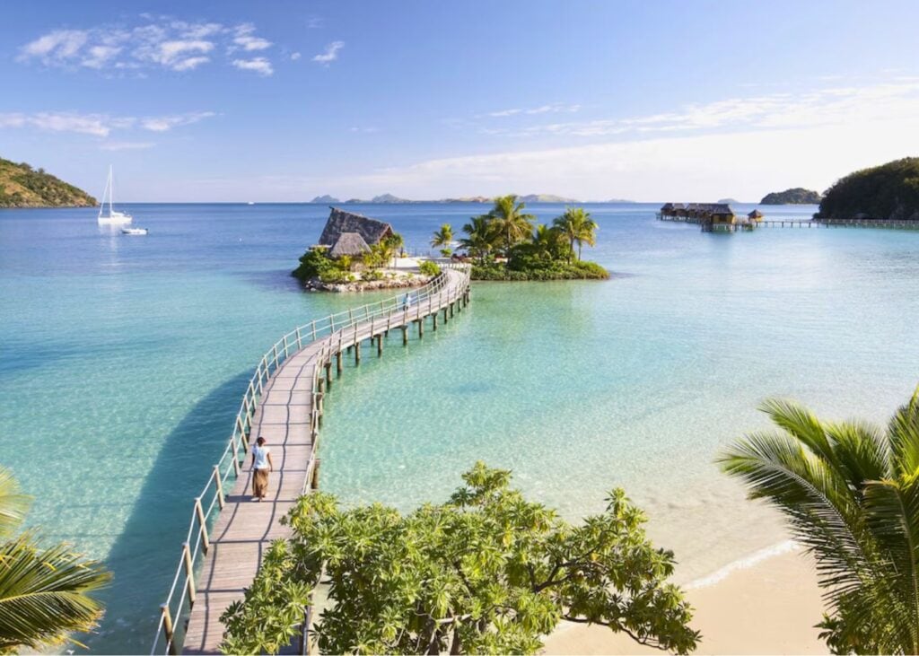 Traditional overwater bungalows at Likuliku Resort in Fiji with turquoise water and lush hills
