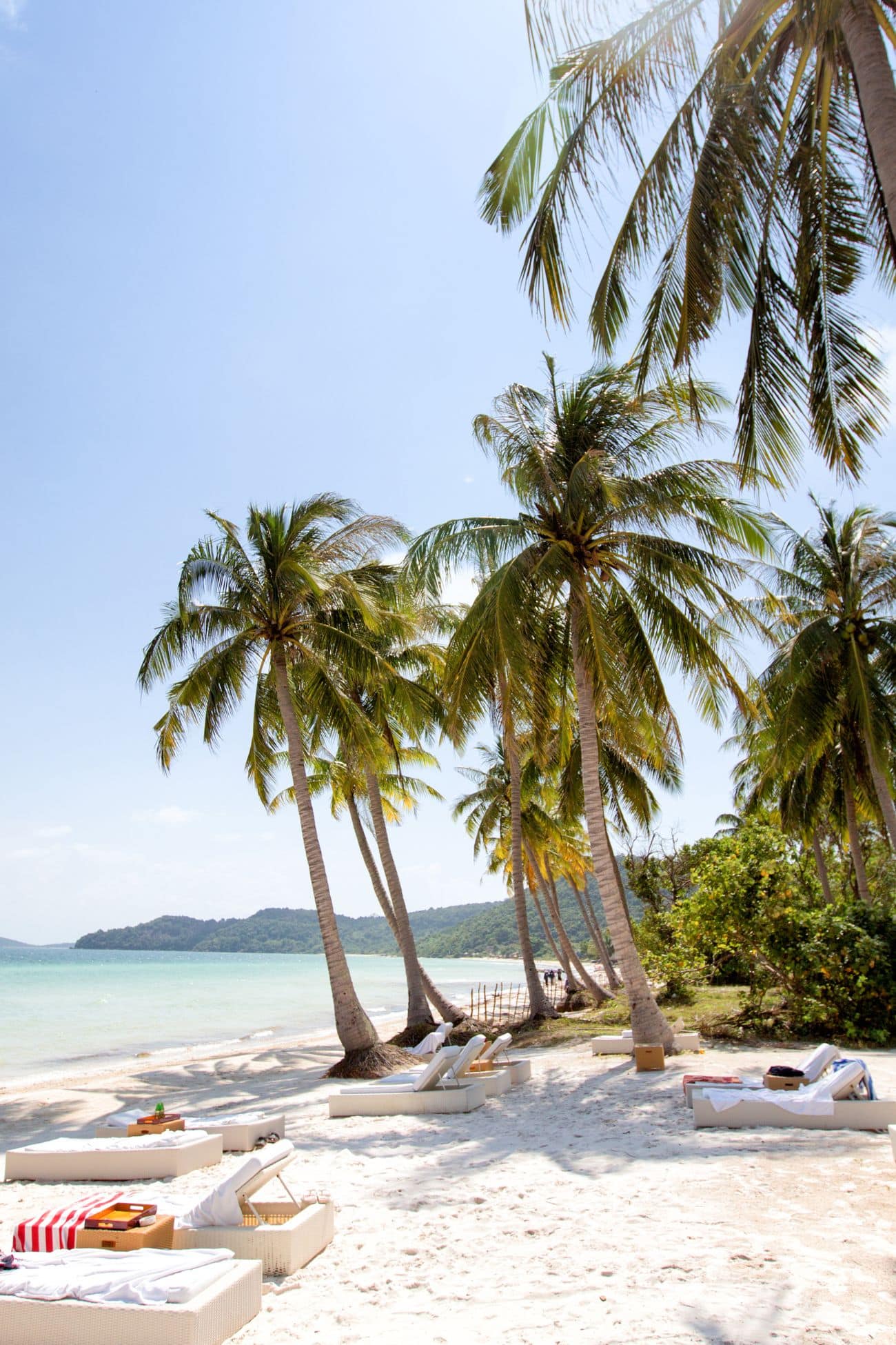 Beachside palm trees and lounge chairs on white sand in Phu Quoc, perfect for relaxing by the ocean.