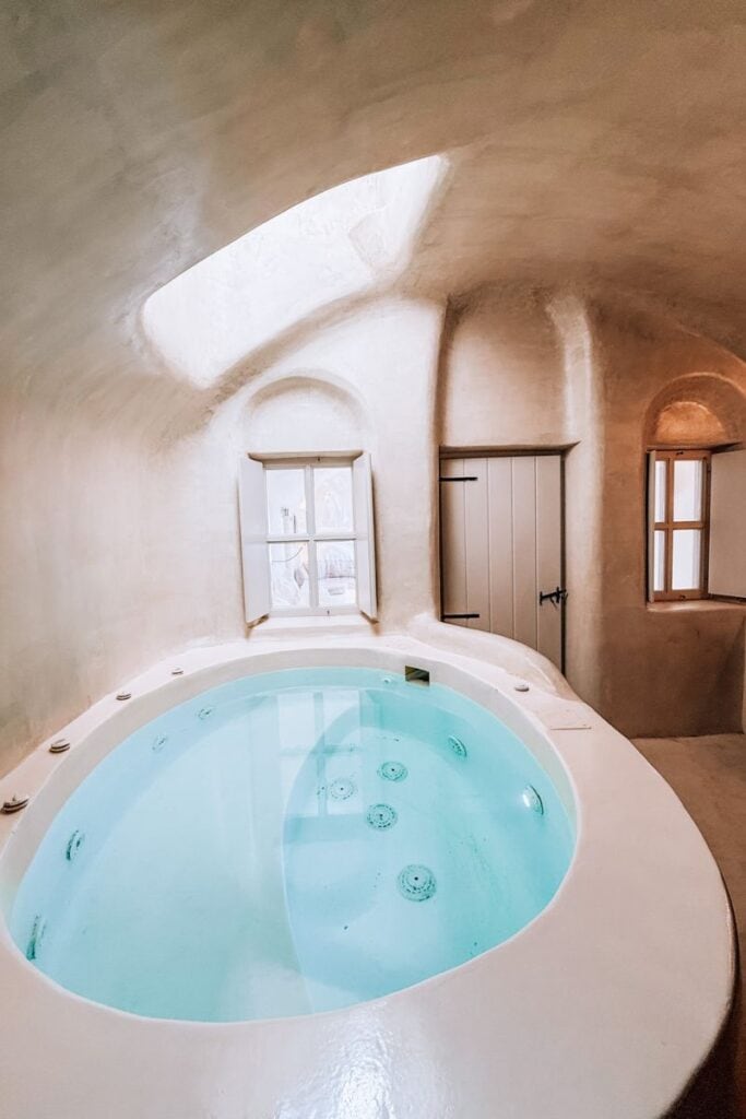 Relaxing indoor hot tub in a cozy Santorini cave hotel with natural light and minimalist decor.
