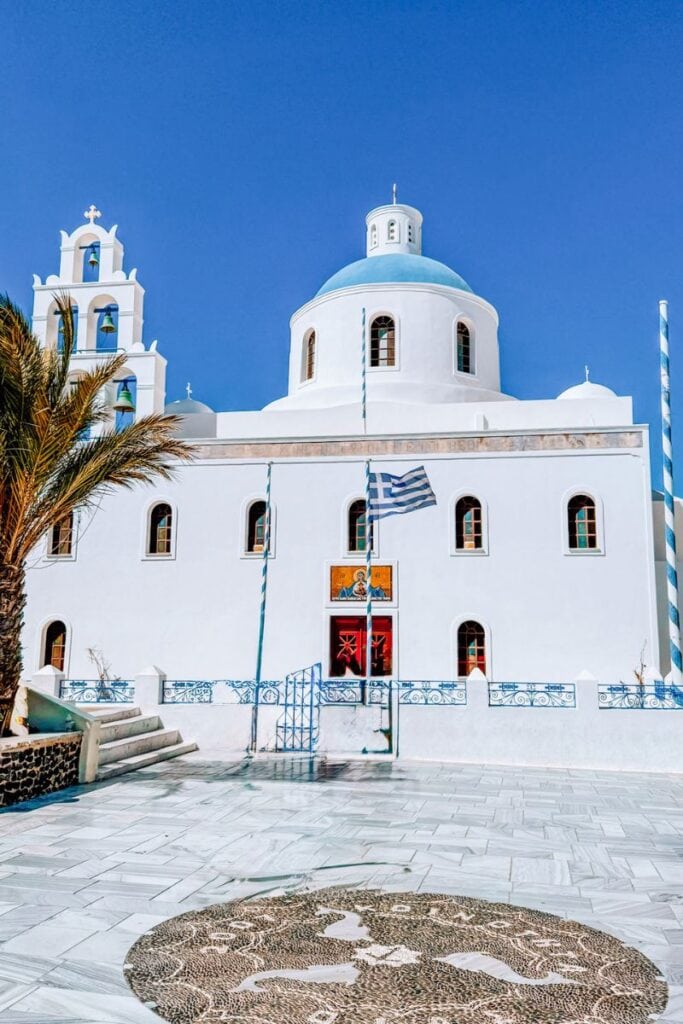 A picturesque white church with blue domes in Santorini, Greece, surrounded by clear skies and traditional island charm, ideal for romantic travel.
