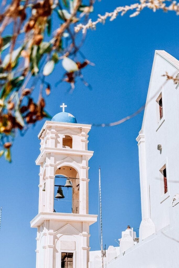 A stunning view of a white Santorini church bell tower against a clear blue sky, perfect for travel inspiration and vacation planning.