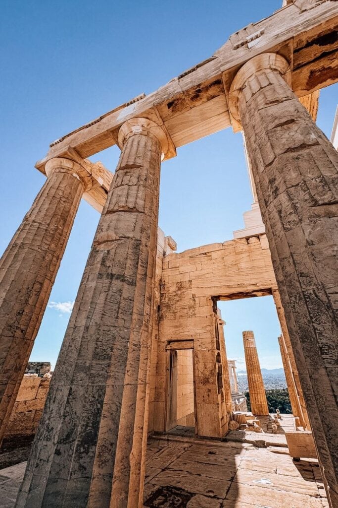 Iconic ancient Greek temple ruins in Athens with towering columns under a clear blue sky.