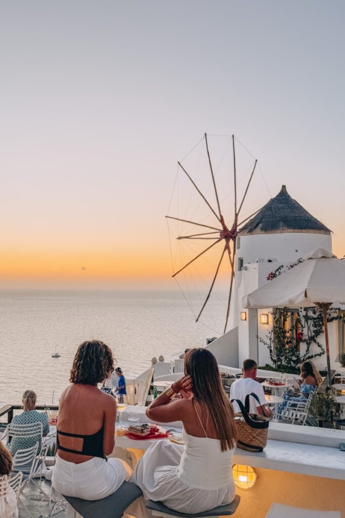 Relaxing sunset at a Greek seaside tavern with friends, perfect for enjoying local cuisine and ocean.