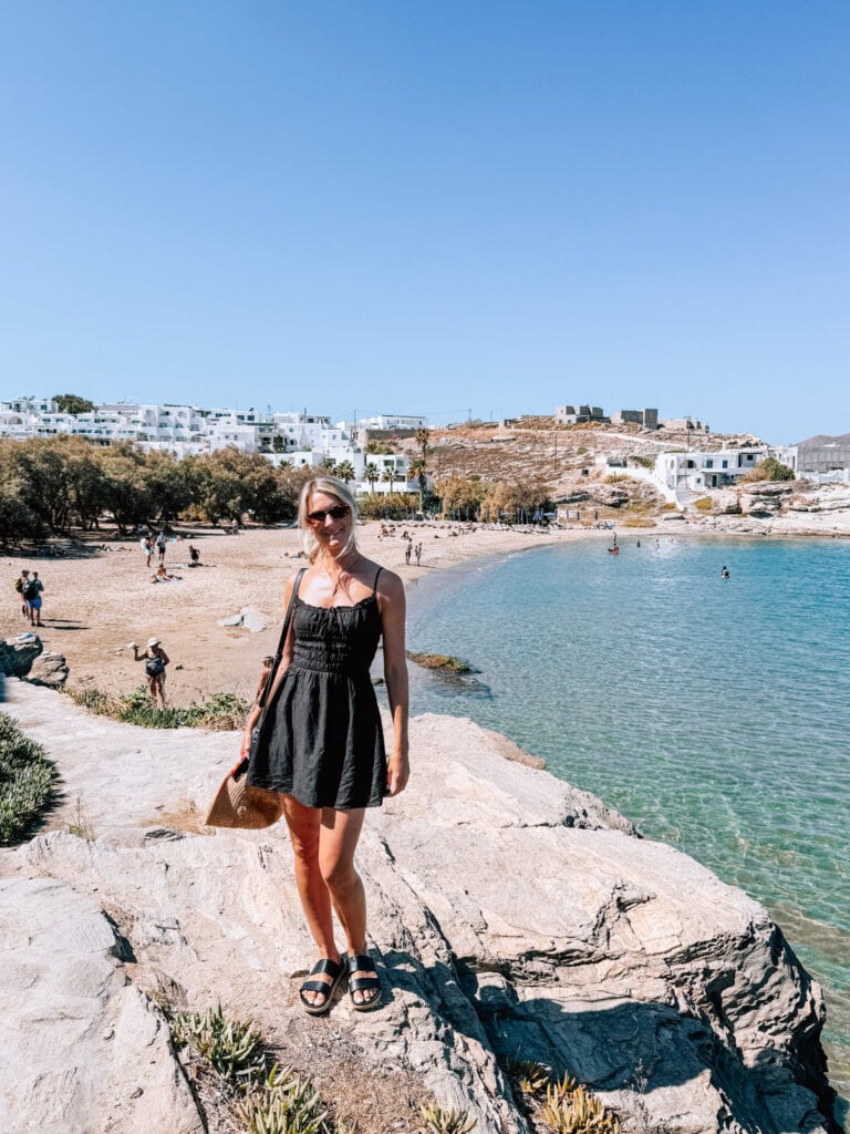 Beach scene with woman in black dress by the water in Paros.