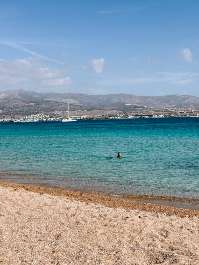 Person swimming in the calm, turquoise waters of Paros beach, Greece.