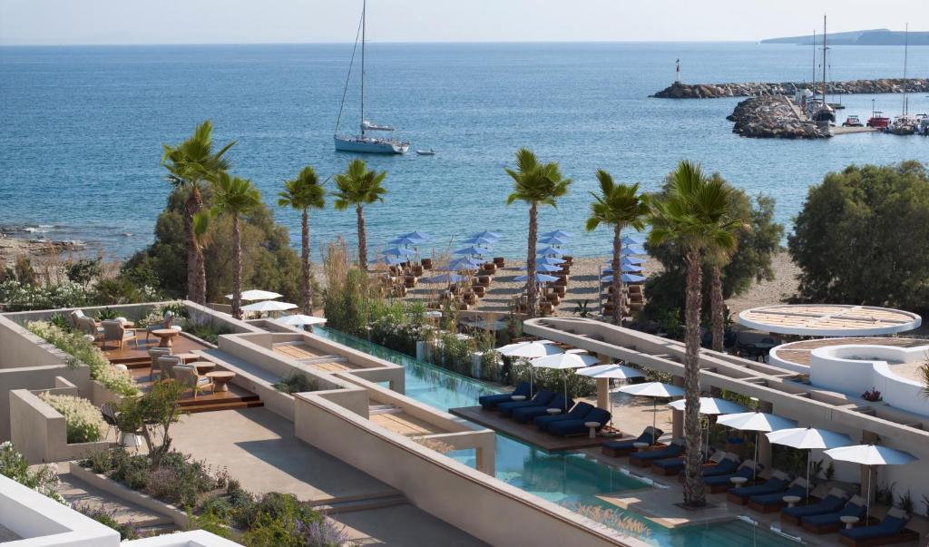 Paros hotel pool area with ocean view, palm trees, and lounge chairs.